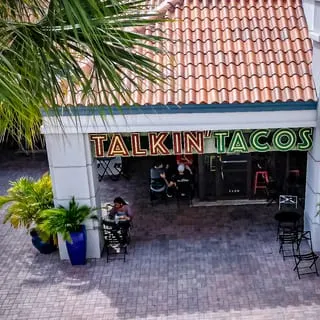 Overhead view of Talkin' Tacos restaurant entrance with outdoor seating and palm trees.
