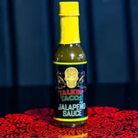 A bottle of Talkin' Tacos Jalapeño Sauce with a yellow cap and a sugar skull label.