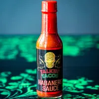 A bottle of Talkin' Tacos Habanero Sauce with a skull logo on a green and blue background.