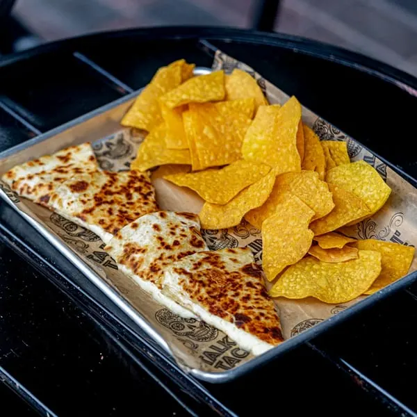 Talkin' Tacos quesadillas and tortilla chips served on a metal tray with branded paper.