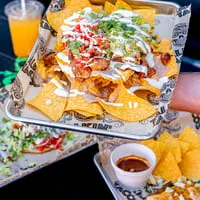 A tray of Talkin' Tacos nachos with chicken, guacamole, pico de gallo, and sour cream.