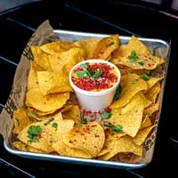 Talkin' Tacos' nachos with a cup of cheese dip, topped with red seasoning and cilantro.