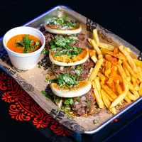 Four Talkin' Tacos birria tacos with fries and a side of consommé on a metal tray.