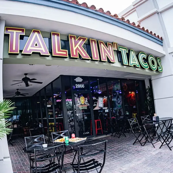 The exterior of Talkin' Tacos restaurant with outdoor seating and food on tables.